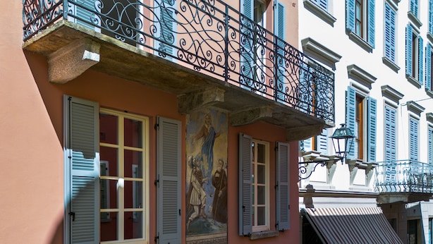Un edificio con balcón, persianas y un mural.