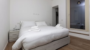Un dormitorio moderno con una cama grande, mesitas de noche y una ventana con vistas.