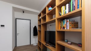 Una sala de estar moderna con una estantería de madera, un televisor de pantalla plana y una puerta.