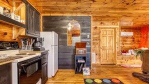 Una cocina acogedora de estilo rústico con paredes de madera, un refrigerador, estufa y cafetera.