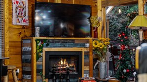 Un salon chaleureux avec une cheminée, un téléviseur fixé au-dessus et un sapin de Noël.