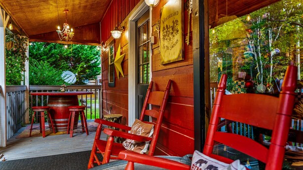 Un espace extérieur accueillant avec des chaises et une table en bois, une décoration en forme d’étoile sur le mur et une enseigne sur laquelle on peut lire : « Wonderland dans les Smokies ».