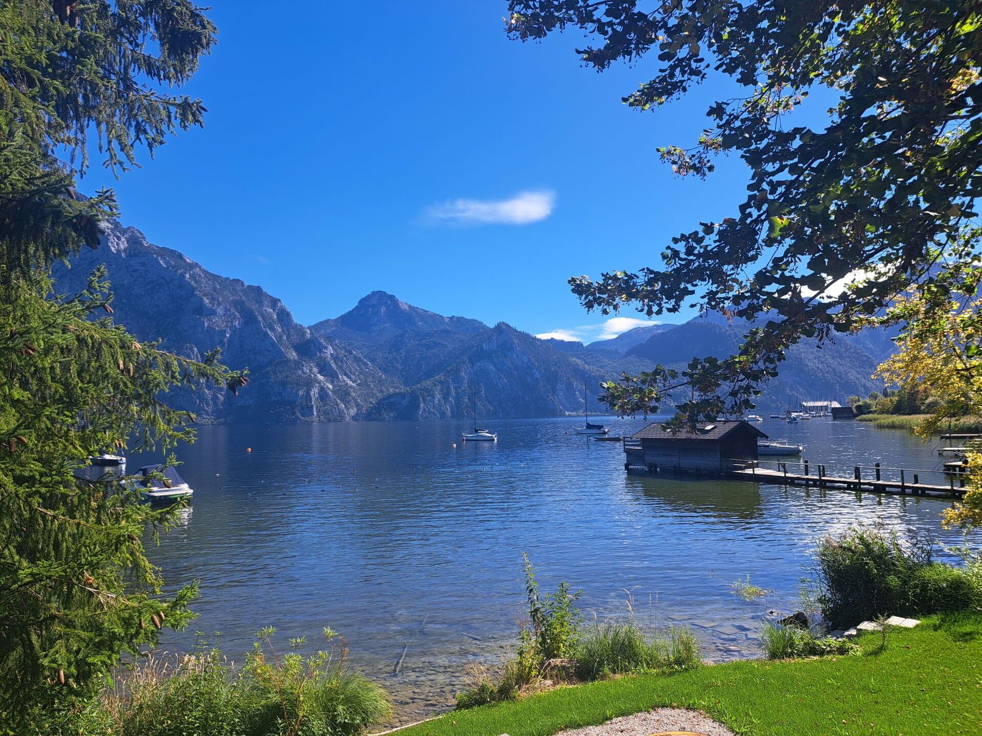 A serene lake with boats, a dock, and mountains in the background.