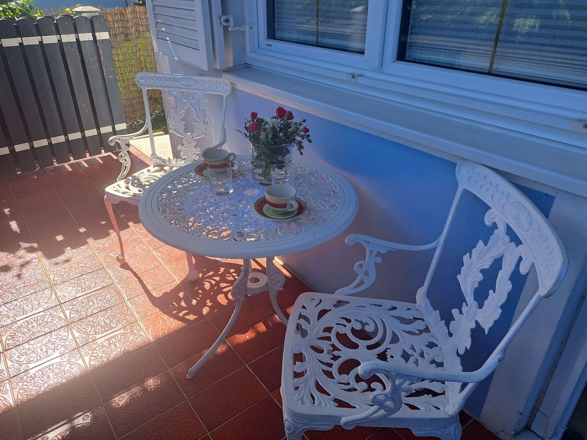 Uma área de estar externa com mesa, cadeira, planta em vaso e um detalhe decorativo na parede.