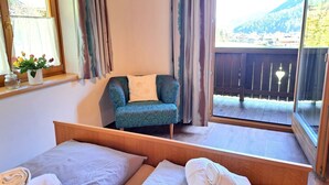 A bedroom with two beds, a chair, and a balcony with a view of a mountain. - Wonderful private villa for 9 guests with TV, balcony, pets allowed and panoramic view (Wald Im Pinzgau)