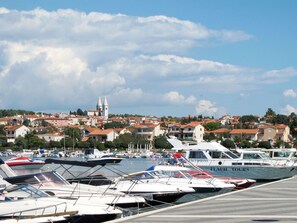 A marina with boats docked, a church in the background, and a town with red-roofed buildings.