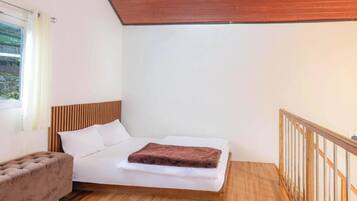 Un dormitorio con cama, cabecera de madera, ventana con cortinas, piso de madera y baranda de madera.