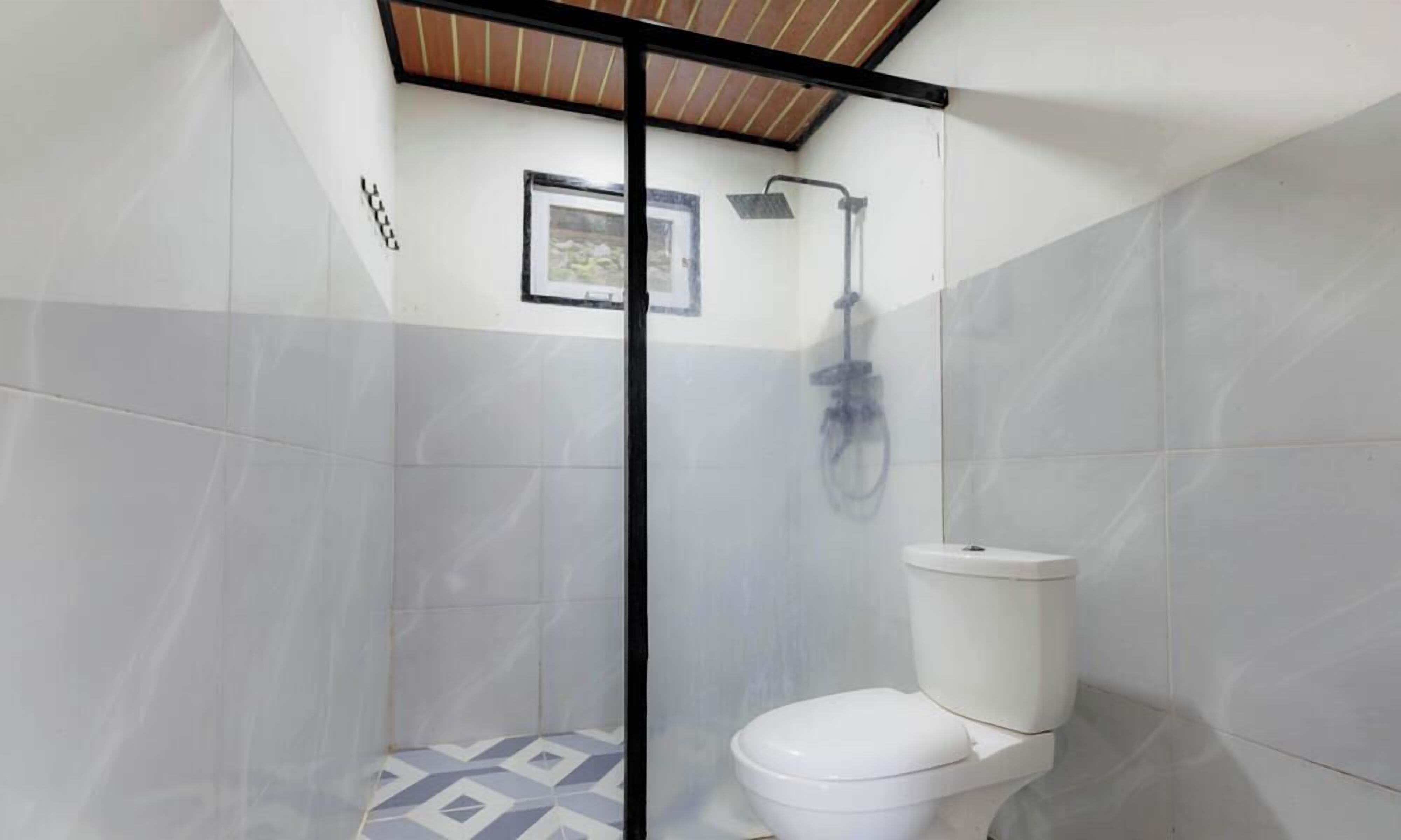 Une salle de bain avec douche, toilettes et murs carrelés.