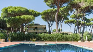 Una piscina circondata da alberi e un edificio con tetto piatto.