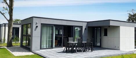 A modern house with a patio area featuring a table and chairs.