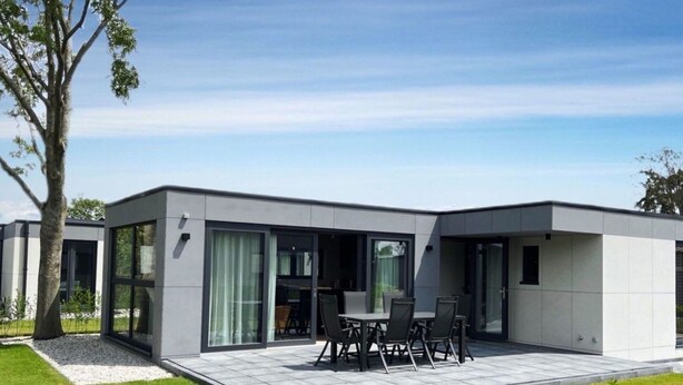 Une maison moderne dotée d’un patio comprenant une table et des chaises.