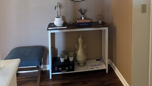 Une pièce comprenant une console blanche, un miroir, un banc et un meuble blanc agrémenté d’objets décoratifs.