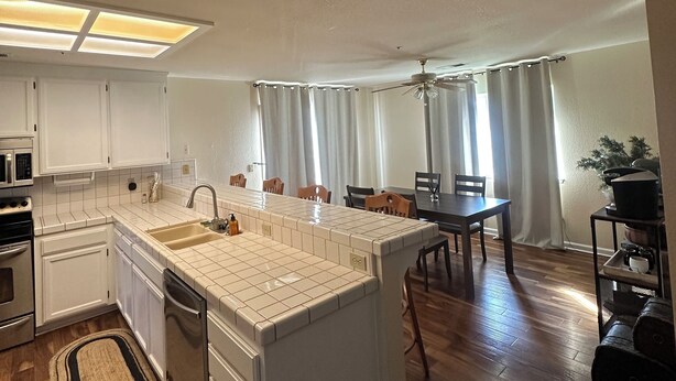 Une cuisine moderne avec des meubles blancs, un grand îlot central et un coin repas comprenant des chaises et une table en bois.