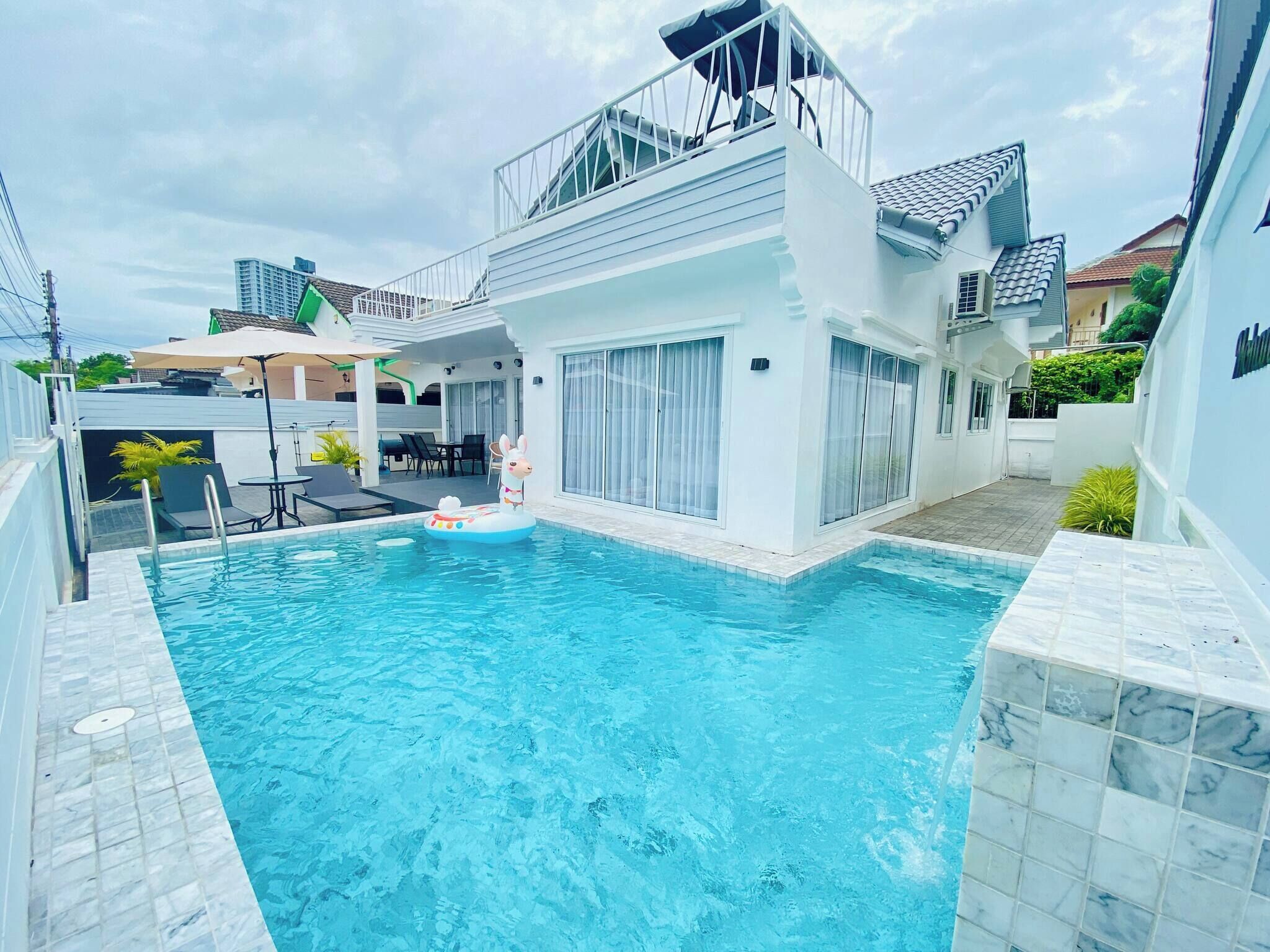 A modern house with a swimming pool, a balcony, and a patio area.