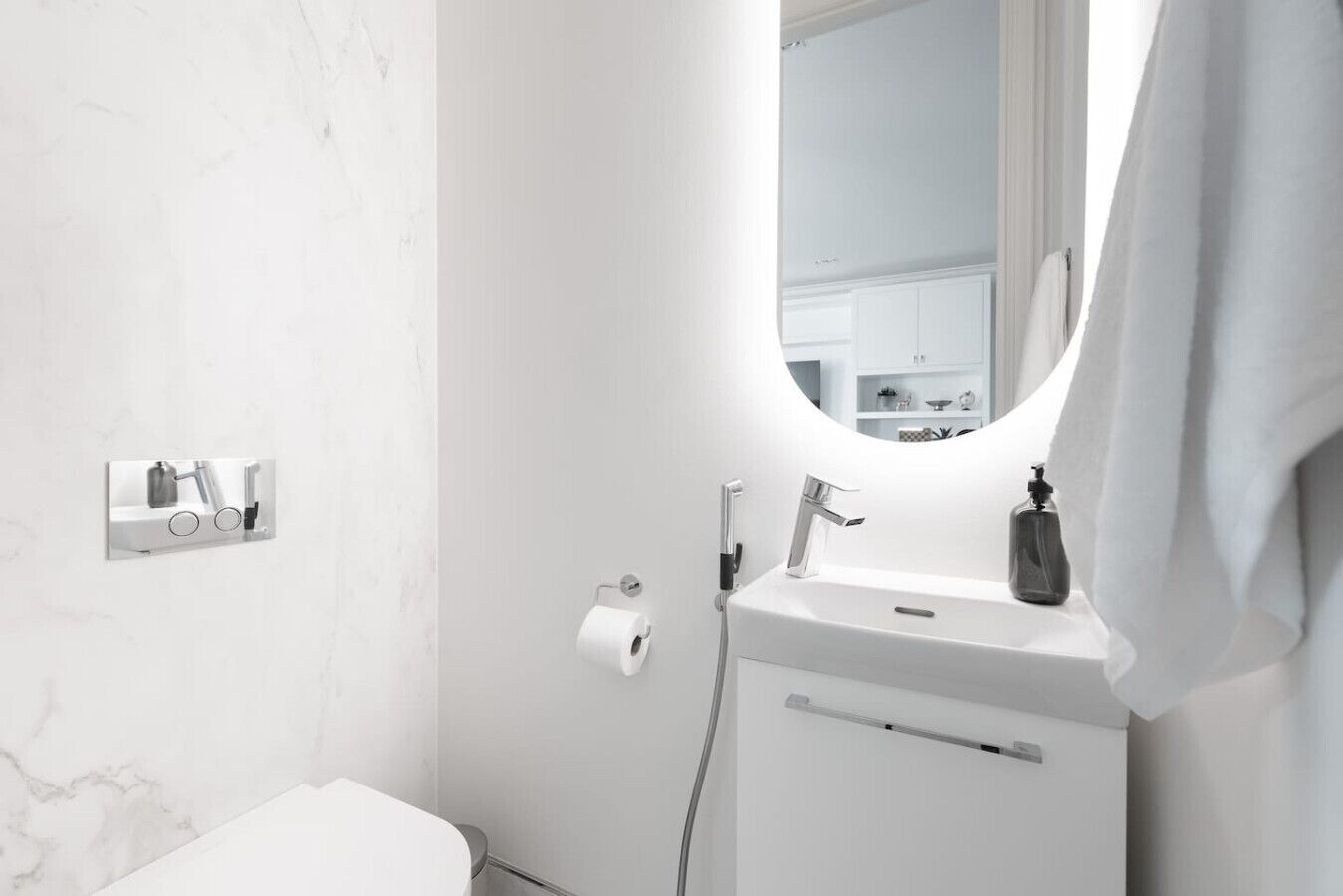 A modern bathroom with a white sink, a mirror, and a toilet.