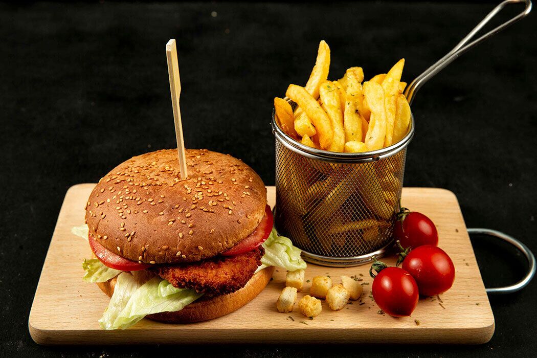 Ein Burger mit Pommes auf einer Holzbrett.