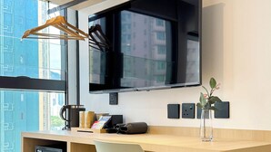 Ein moderner Arbeitsplatz mit einem Holztisch, einem weißen Stuhl, einem schwarzen Bildschirm und einer Kaffeemaschine.
