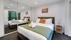 A hotel room with a large bed, a mirror, a nightstand, a lamp, and a painting on the wall.