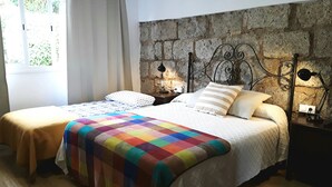 A double bed with a colorful quilt, a stone wall behind, and a window with curtains. - El Trazo, perfect to disconnect. (tacoronte)