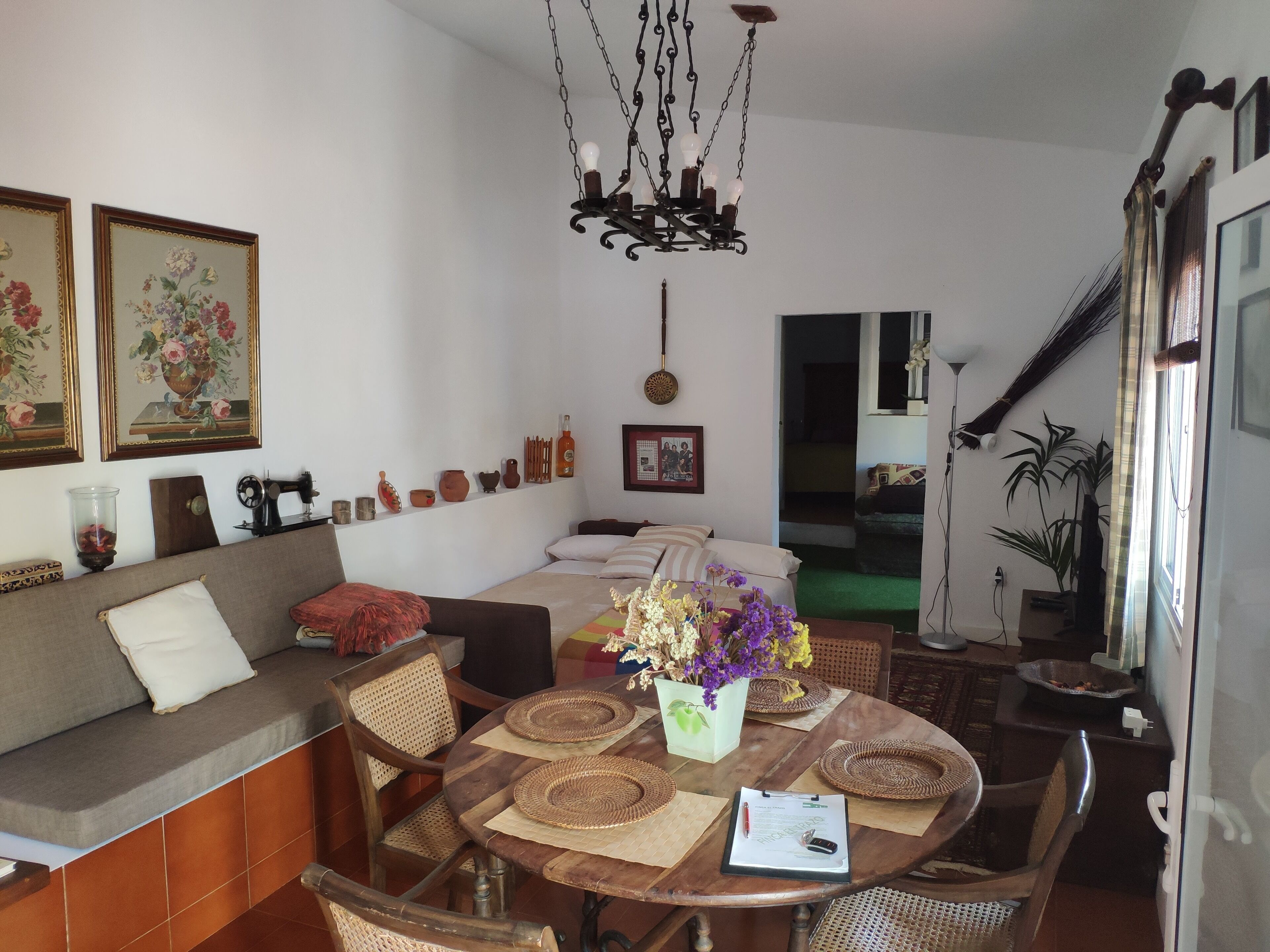 Uma área de refeições acolhedora com mesa de madeira, jogos americanos trançados e um vaso de flores.