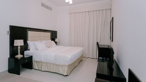 Una habitación de hotel con una cama grande, una mesita de noche con lámpara, televisión y ventana con cortinas.