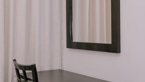 Una habitación con un escritorio de color oscuro, una silla y un espejo en la pared.