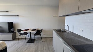 Une cuisine moderne avec un coin repas, comprenant un téléviseur à écran plat, une table à manger avec des chaises et une cuisinière encastrée.