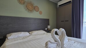 Une chambre d’hôtel comprenant un lit, des éléments de décoration murale, un appareil de climatisation et une table de chevet avec une lampe.