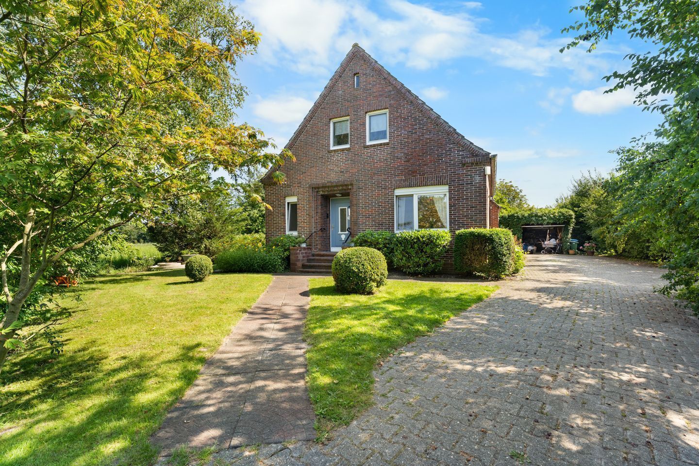 A two-story brick house with a paved driveway and a well-maintained lawn.