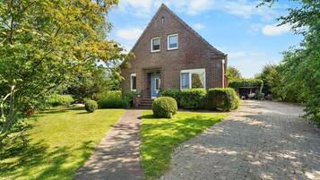 A two-story brick house with a paved driveway and a well-maintained lawn.