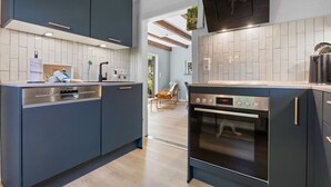 Una cocina moderna con armarios oscuros, horno empotrado y lavavajillas de acero inoxidable.