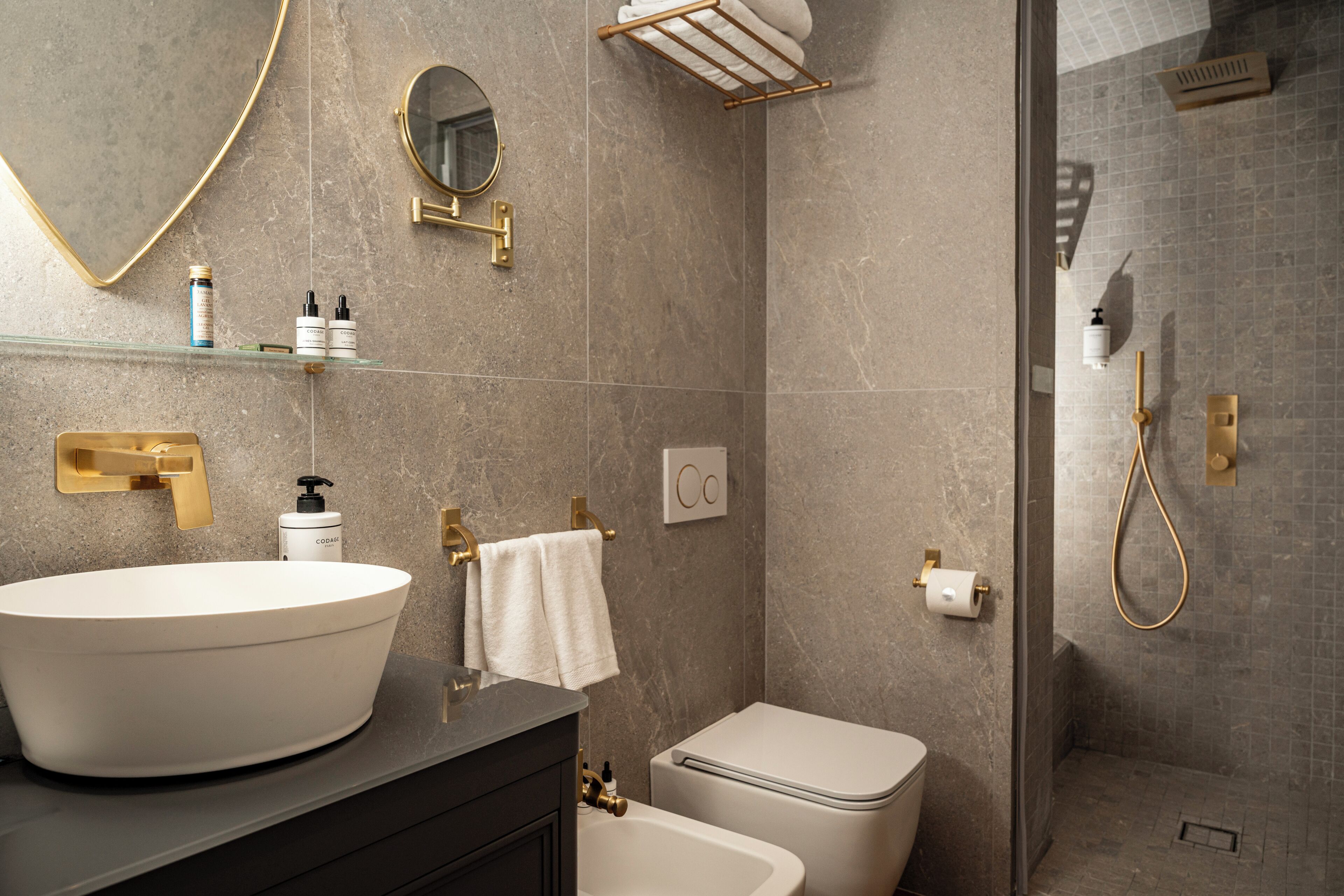 A modern bathroom with a large vessel sink, a toilet, a shower area, and a mirror.