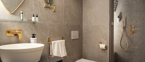 Un baño moderno con un lavamanos de diseño, inodoro, zona de ducha y espejo.