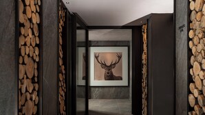 A hallway with a framed deer head artwork, stone walls, and a tiled floor. - Hotel Livata Mountain Wellness  (Subiaco)