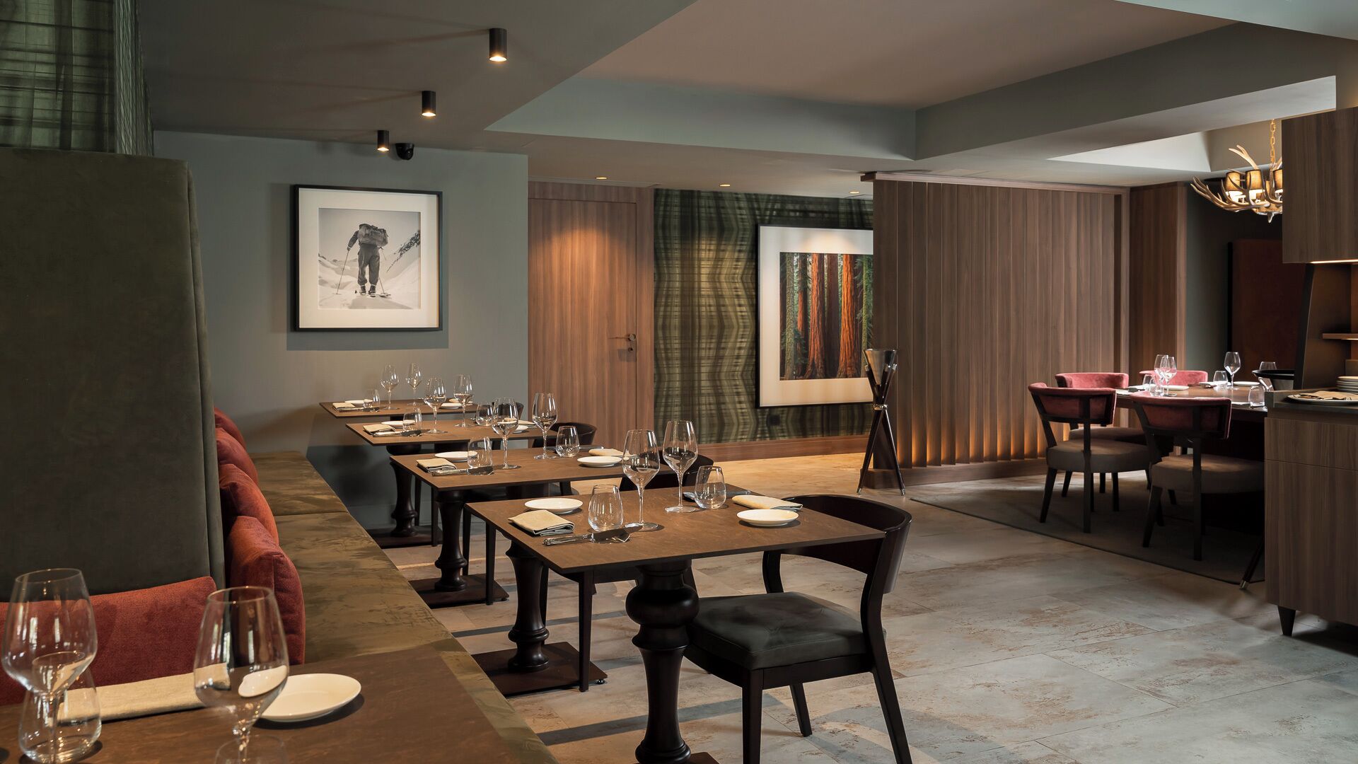 A dining area with multiple tables set for a meal, a bar area with stools, and a framed picture on the wall.