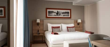 Una habitación de hotel con cama, mesitas de noche, un escritorio y una silla.