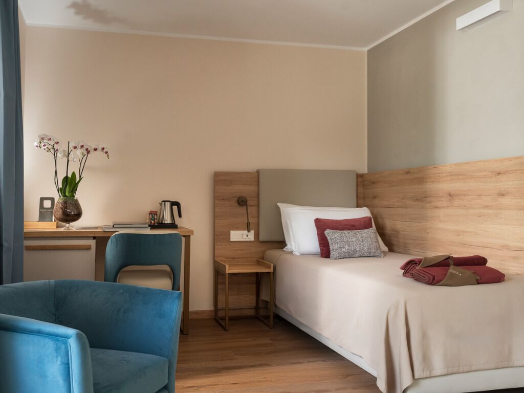 Une chambre d’hôtel avec un lit, un bureau, une chaise et une petite table.