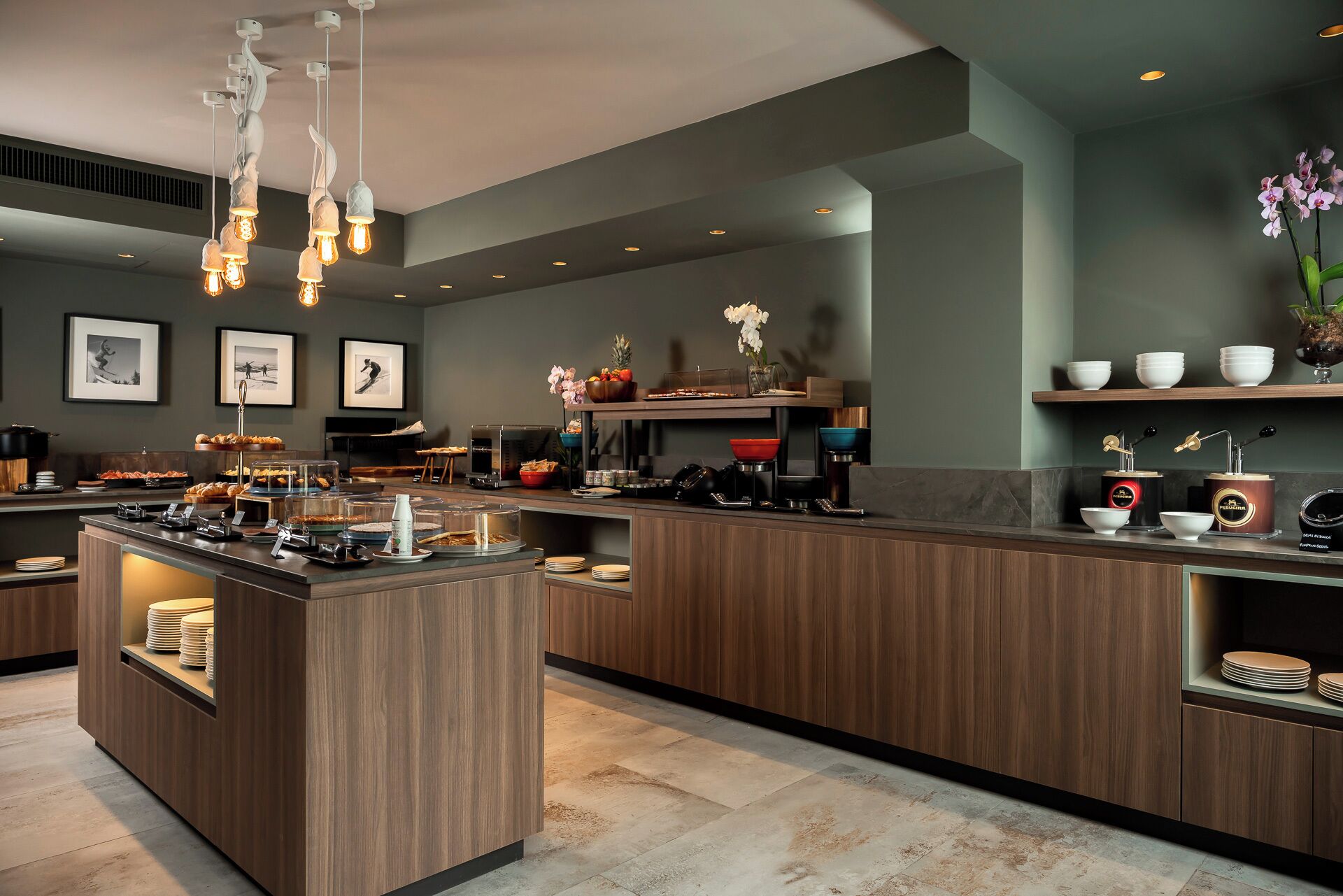 Un moderno vestíbulo de hotel con un mostrador de recepción central, obras de arte enmarcadas en las paredes y diversas comodidades, como una estación de café y una exhibición de frutas.