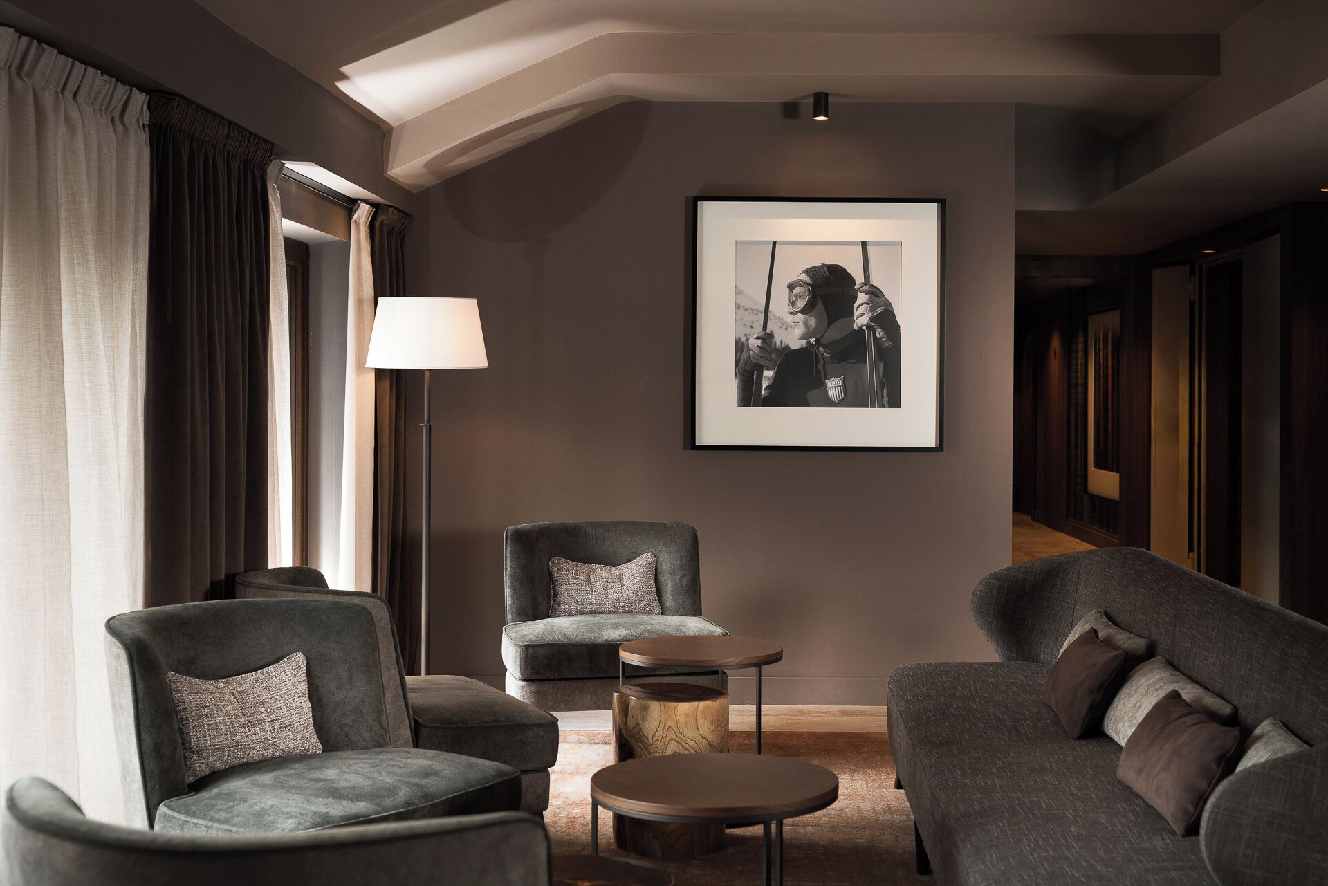 A modern living room with a sofa, armchairs, a lamp, and a framed picture on the wall.