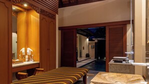 A spa room with a massage table, a stone sink, and wooden cabinets. - Villa Elegant by Exotiq (Seminyak)