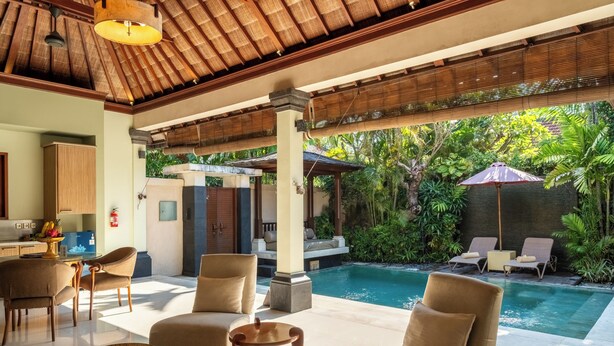 A modern indoor pool area with lounge chairs, a dining area, and a kitchen. - Villa Elegant by Exotiq (Seminyak)