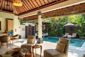 A modern indoor pool area with lounge chairs, a dining area, and a kitchen. - Villa Elegant by Exotiq (Seminyak)