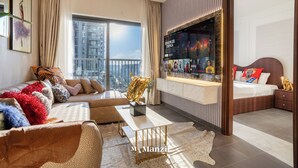 A modern hotel room with a large window, a sofa, a dining table, and a TV mounted on the wall. - Manzil - Stylish 1BR with Pool and Gym  (Dubai)