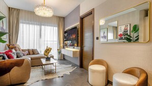 A modern living room with a sofa, armchair, coffee table, and a chandelier. - Manzil - Stylish 1BR with Pool and Gym  (Dubai)