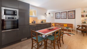 Una cucina moderna con elettrodomestici integrati, un'area pranzo con sedie in legno, un divano e un tavolino.