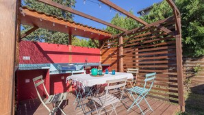 Un patio in legno con tavolo e sedie, un barbecue e una pergola.