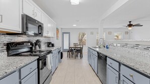 Una cocina moderna con encimeras de granito, electrodomésticos de acero inoxidable y una zona de comedor con mesa y sillas.