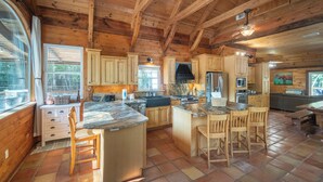 A spacious kitchen with wooden cabinets, a large island, and a dining area with chairs.