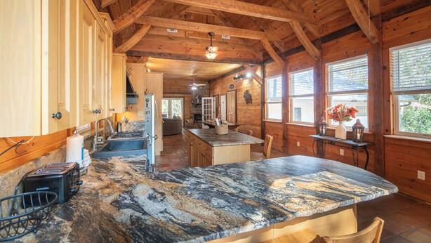A kitchen with granite countertops, wooden cabinets, and a large island.