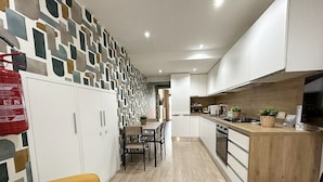 A modern kitchen with white cabinets, a wooden countertop, and a dining area with a yellow sofa.
